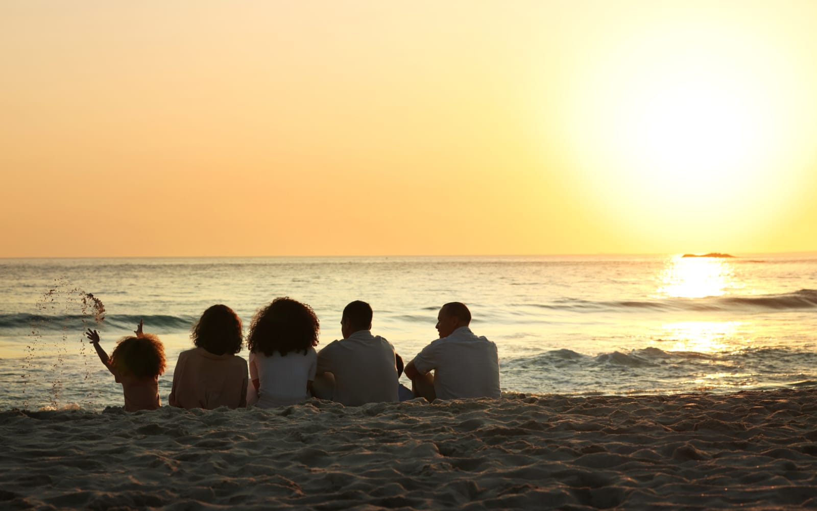 A family sitting together on the beach at sunset